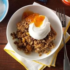 a white bowl filled with granola and topped with whipped cream on top of a wooden table