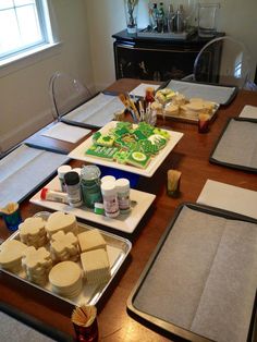 there are many trays on the table with cakes and condiments in them