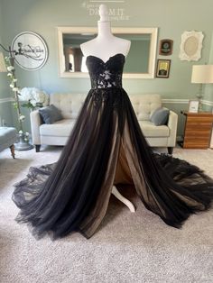 a black and white dress on display in front of a couch with a mirror behind it