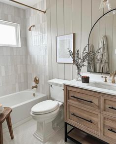 a white toilet sitting next to a bath tub in a bathroom under a mirror above a sink