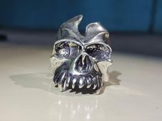 This handcrafted sterling silver Gothic Skull Ring is perfect for those who love bold, unique, and edgy jewelry. Made from high-quality 925 sterling silver, this intricately detailed ring features a fierce skull design, making it the ideal accessory for those who appreciate alternative fashion styles like gothic, punk, and rock. The ring's eye-catching design and substantial weight make it a standout piece for any collection. Its polished finish enhances the silver's natural luster, adding a pre Rock Ring, Sterling Silver Skull Rings, Rock Rings, Silver Skull Ring, Edgy Jewelry, Gothic Skull, Gothic Punk, Detailed Ring, Ring For Men