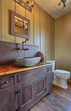 a bathroom with a sink, toilet and wood paneled walls