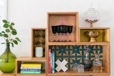 a wooden shelf with vases, books and other decorative items on top of it