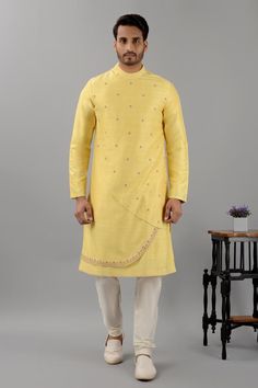 Pale yellow raw silk kurta with band collar, overlap asymmetric panels, floral pattern contrast thread and bead embroidery. Paired with white gathered churidar.
Components: 2
Pattern: Embroidered
Type Of Work: Thread and Bead Work
Neckline: Band Collar
Sleeve Type: Full Sleeves
Fabric: Raw Silk
Color: Yellow
Other Details: 
Curved panel hem
Side slits on kurta
Kurta Closure: Shoulder concealed zip
Occasion: Destination Wedding,Sangeet - Aza Fashions Ceremonial Raw Silk Kurta With Cutdana, Gold Slub Silk Kurta For Transitional Season, Gold Chanderi Bandhgala With Traditional Drape, Gold Bandhgala In Chanderi With Traditional Drape, Transitional Gold Slub Silk Kurta, Gold Raw Silk Bandhgala With Cutdana Detailing, Gold Raw Silk Bandhgala With Cutdana, Ceremonial Chanderi Kurta With Cutdana, Ceremonial Art Silk Kurta With Cutdana