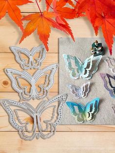 some paper butterflies are sitting on a piece of cloth next to autumn leaves and red maple leaves