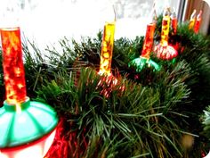 some candles that are sitting on top of a christmas tree in front of a window