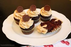 chocolate cupcakes with white frosting and heart shaped decorations on a paper plate