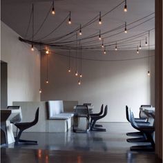 an empty room with many chairs and lights hanging from it's ceiling over the dining table