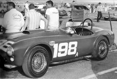 black and white photograph of an old race car with two men in the back seat