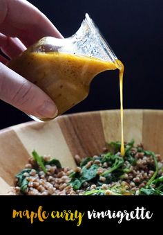 someone pouring dressing into a wooden bowl filled with spinach and lentils