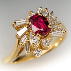 a gold ring with a red stone surrounded by white and clear stones