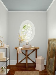 a bathroom with blue walls and wood flooring has a round window in the corner