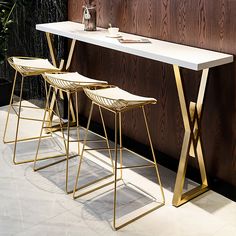 three stools and a table in front of a wooden wall