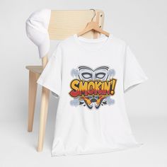 Turn up the heat with our 'Smokin' T-Shirt, inspired by a classic catchphrase from a beloved 90s comedy! This tee is a must-have for fans of retro movies and iconic pop culture quotes. Made with premium, soft cotton, this shirt is perfect for everyday wear or as a standout piece in your collection. The bold design and striking typography make it a great conversation starter, while the comfortable fit ensures you can wear it all day with ease. Whether you're a movie buff, a lover of 90s nostalgia Cheap Pop Culture Graphic T-shirt, Cheap Pop Culture T-shirt With Character Print, Cheap Pop Culture T-shirt With Custom Artwork, Retro Pop Culture, Pop Culture Quotes, Retro Movies, Culture Quotes, Retro Pop, Movie Buff