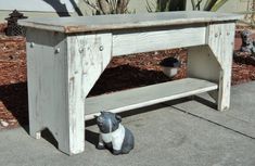 an old wooden table with a small dog figurine underneath it on the sidewalk