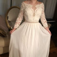 a woman in a white dress standing next to a mirror and looking at the camera