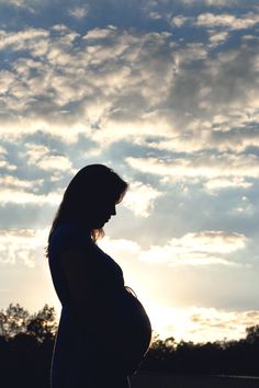 a pregnant woman is silhouetted against the sky