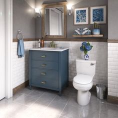 a white toilet sitting under a bathroom mirror next to a blue sink and counter top