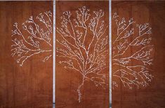 three paneled wall art with white branches on brown wood panels, one is painted and the other is made from metal