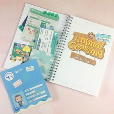 an animal crossing book with stickers on the pages and a notebook next to it