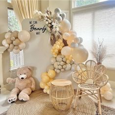 there is a teddy bear sitting on the floor next to balloons and other decorations in front of a window