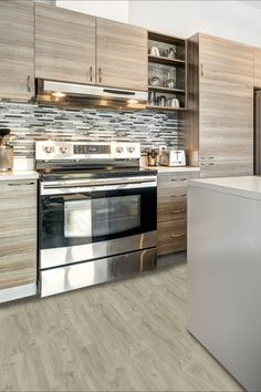 a modern kitchen with stainless steel appliances and wood cabinetry on the walls, along with white countertops