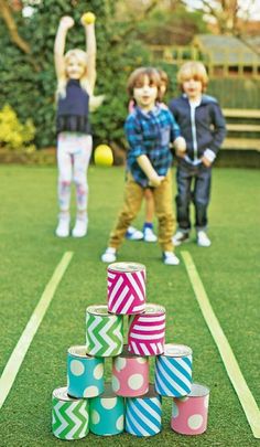 three children are standing on the grass with cups in front of them