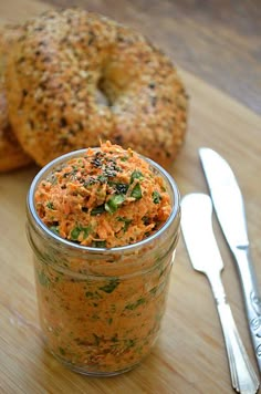 a jar filled with food next to two bagels on top of a wooden table