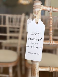 a sign that says reserved for the bridesmaid hanging from a wooden chair with chairs in the background