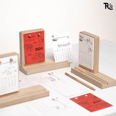 a desk with calendars, pens and magnets sitting on top of each other