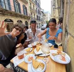 some people are sitting at a table with plates of food and drinks in front of them