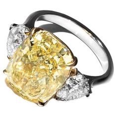 This exquisite ring features a GIA-certified 5.24-carat fancy yellow cushion-cut diamond, elegantly set in 18K white gold, with the upper portion supporting the central stone crafted in 18K yellow gold. The vibrant fancy yellow diamond captivates with its rich color, enhanced by the warm tones of the yellow gold setting.Accompanying the centerpiece are two pear-cut diamonds that add an element of sophistication and brilliance. The diamond's VVS2 clarity grade ensures it is nearly flawless, with Luxury Yellow Gold Diamond Ring In Recycled Gold, Luxury Yellow Gold White Topaz Ring, Luxury Gold Multi-stone Diamond Ring, Dream Rings, Yellow Cushion, Elongated Cushion Cut, Cushion Cut Diamond Ring, Elongated Cushion, Yellow Cushions