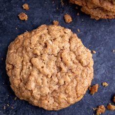 an oatmeal cookie sitting on top of a blue surface next to another cookie