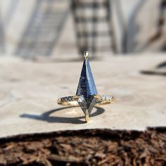 a blue diamond ring sitting on top of a piece of wood next to a chair