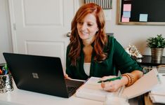 a woman sitting at a desk with a laptop and notepad in front of her