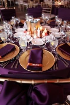 the table is set with purple linens and place settings