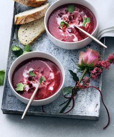 two bowls of beet soup with bread and flowers