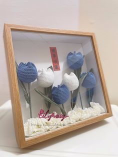 there are crocheted blue and white flowers in a shadow box