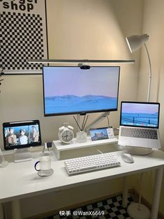 two laptops and a desktop computer on a desk in front of a large screen