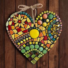 a colorful heart shaped decoration hanging on a wooden wall