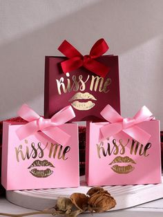 three pink bags with kisses me and kiss me on them, sitting next to each other