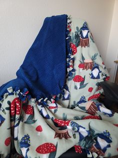 a blue blanket with red and white mushrooms on it is draped over a black chair