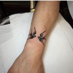 a small tattoo on the wrist of a man with two birds flying above him and one bird below his arm