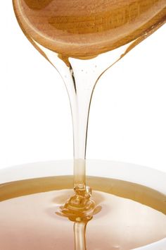 a wooden spoon pouring liquid into a bowl