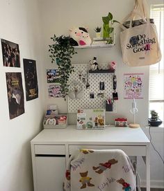 a white desk topped with a chair next to a wall filled with pictures and plants