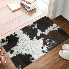 a cowhide rug is on the floor next to a pair of slippers and a book