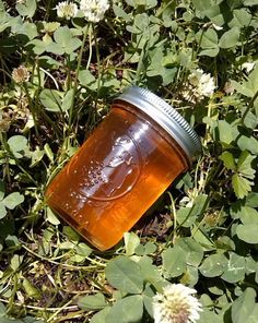 a jar sitting in the grass with flowers around it