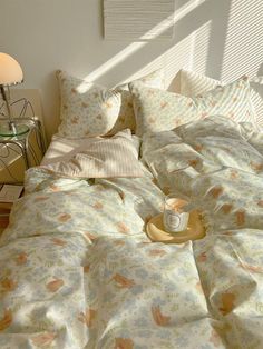 an unmade bed in a bedroom with white walls and light coming through the window