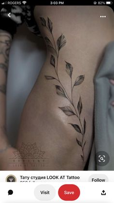 the back of a woman's thigh with leaves on it and an arrow tattoo