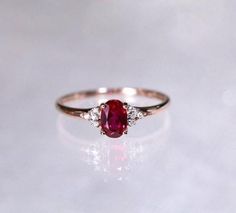 an oval shaped ruby and diamond ring on a white surface